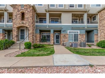 Inviting condo exterior featuring stone accents, a well-maintained lawn, and a sidewalk to the front door at 457 Black Feather Loop # 702, Castle Rock, CO 80104