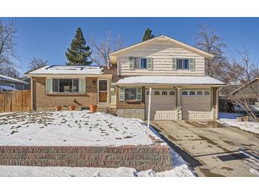 Brick house with two-car garage and snow-covered yard at 9235 Quitman St, Westminster, CO 80031