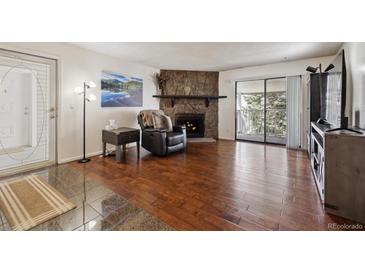 Comfortable living room with a stone fireplace and access to the balcony at 943 S Zeno Way # 207, Aurora, CO 80017