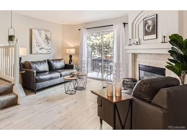 Bright living room featuring a fireplace, hardwood floors, and sliding glass doors to the balcony at 8264 S Fillmore Way, Centennial, CO 80122