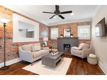 Cozy living room with brick accent wall, fireplace, and neutral-toned furniture; ceiling fan above at 3176 Depew St, Wheat Ridge, CO 80214