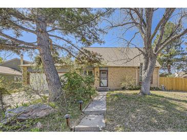 Charming brick home featuring a well-manicured lawn and mature trees enhancing its curb appeal at 14742 E Radcliff Pl, Aurora, CO 80015