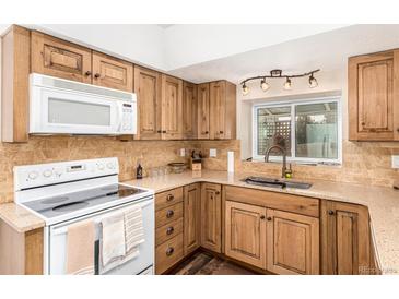 Modern kitchen with wood cabinets, granite countertops and a built-in microwave at 6119 Zenobia Ct, Arvada, CO 80003