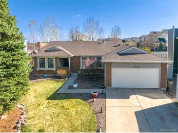 Charming single-story brick home featuring a well-maintained lawn and an attached two-car garage in a residential neighborhood at 5370 W 74Th Ave, Arvada, CO 80003