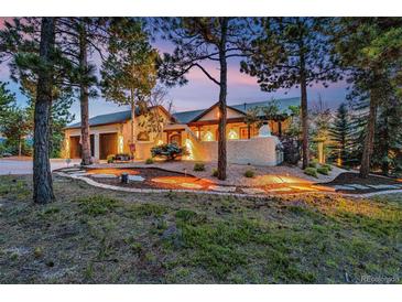 Stunning home exterior with stucco walls, mature trees, and warm lighting creating a welcoming ambiance at 17995 Minglewood Trl, Monument, CO 80132
