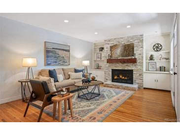 Cozy living room featuring a stone fireplace, built-in shelves, and stylish decor with a patterned rug at 5523 E Utah Pl, Denver, CO 80222