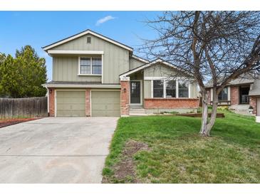 Charming two-story home featuring a well-maintained lawn, brick accents, and an attached two-car garage at 8174 Field Cir, Arvada, CO 80005