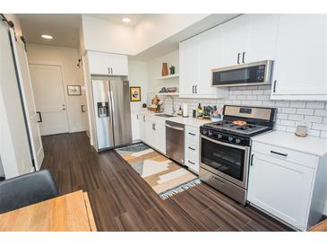 Stylish kitchen with stainless steel appliances, subway tile backsplash, and sleek white cabinetry at 2876 W 53Rd Ave # 106, Denver, CO 80221