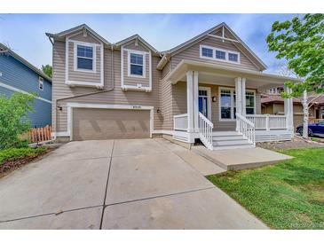 Charming two-story home featuring a covered porch, two-car garage, and manicured lawn at 8545 Braun Loop, Arvada, CO 80005