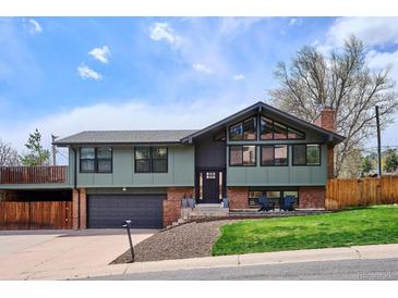 Charming home featuring a two-car garage, unique architectural details, and a well-maintained front yard at 13588 W Exposition Dr, Lakewood, CO 80228