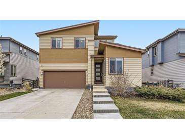 Two-story home with a brown garage door, light-yellow siding, and a well-manicured lawn at 10808 Salida St, Commerce City, CO 80022