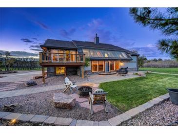 Inviting home exterior with a large glass sunroom, stone patio, fire pit, and well-manicured lawn at 18045 Sunburst Dr, Monument, CO 80132