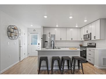 Modern kitchen features sleek white cabinets, stainless steel appliances, and breakfast bar with stylish stools at 1143 Hummingbird Cir, Longmont, CO 80501
