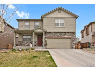 Two-story home featuring stone accents, a two-car garage, and a well-maintained front yard at 12685 E 104Th Pl, Commerce City, CO 80022