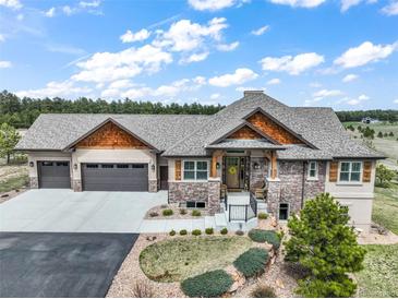 Charming home featuring a stone facade, cedar accents, a three-car garage, and professionally landscaped front yard at 17275 Gwilym Ct, Monument, CO 80132