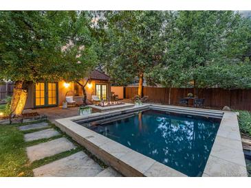 Inviting backyard features a refreshing pool, lounge chairs and a cozy fire pit surrounded by lush greenery at 235 Eudora St, Denver, CO 80220