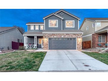 Charming two-story home featuring a brick facade, covered porch, and well-maintained landscaping at 7412 S Mobile St, Aurora, CO 80016