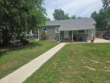 Charming stone home featuring a well-manicured lawn, sidewalk and covered front porch with stylish outdoor decor at 1930 Alton St, Aurora, CO 80010