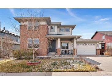 Inviting two-story home featuring a brick facade, covered porch, and well-maintained landscaping at 4464 E 139Th Ave, Thornton, CO 80602