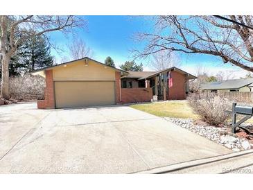 Charming single-story brick home featuring a spacious driveway and mature landscaping on a sunny day at 7019 S Windermere St, Littleton, CO 80120