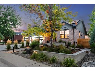 Charming brick home boasts a modern garage door and beautifully landscaped front yard at dusk at 9161 W Lake Dr, Littleton, CO 80123