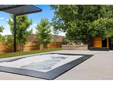 Backyard hot tub with brick feature, privacy fence, pergola, and exterior building at 9161 W Lake Dr, Littleton, CO 80123