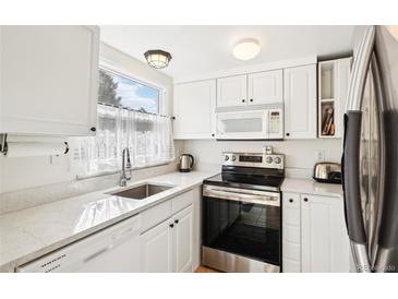 Bright kitchen featuring white cabinets, stainless steel appliances, and quartz countertops at 5959 S Willow Way, Greenwood Village, CO 80111