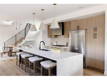 Bright, modern kitchen with stainless steel appliances and a large white marble countertop island with seating at 3437 W 17Th Ave, Denver, CO 80204