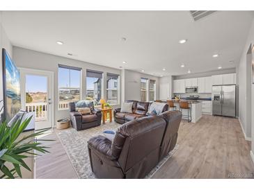 Open-concept living room and kitchen with hardwood floors, stainless steel appliances, and lots of natural light at 1917 S Fultondale Way, Aurora, CO 80018