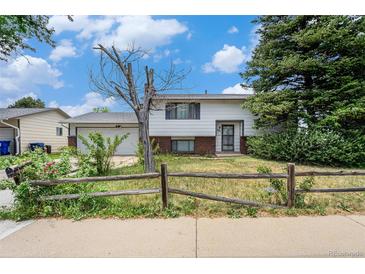 Charming home with a yard featuring a rustic fence and mature trees under a bright sky at 757 Norfolk Way, Aurora, CO 80011