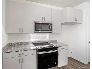 Modern kitchen features stainless steel appliances, granite countertops, and white cabinetry at 22123 E 38Th Pl, Aurora, CO 80019