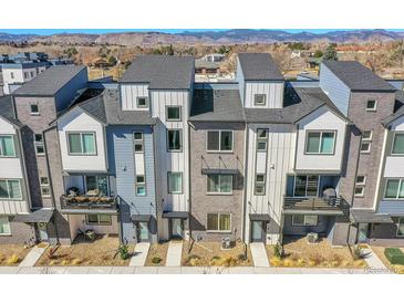 An exterior view of modern townhomes featuring neutral colors, balconies, and mountain views in the background at 5738 N Vivian St, Arvada, CO 80002