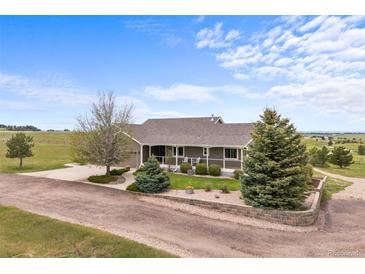 Inviting single-story home with a charming front porch, landscaped yard, and circular drive in a serene rural setting at 6785 Arrowhead Cir, Elizabeth, CO 80107