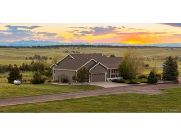 Charming single-Gathering home features a well-manicured lawn and a gravel driveway leading up to a 2-car garage at 6785 Arrowhead Cir, Elizabeth, CO 80107