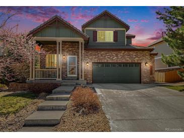 Charming two-story home featuring a brick facade, covered porch, and well-manicured front yard at 24702 E Hoover Pl, Aurora, CO 80016