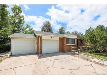 Charming brick home featuring an attached two car garage and a cracked concrete driveway at 12154 E Virginia Dr, Aurora, CO 80012