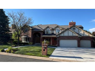 Charming brick two-story home with a tile roof, manicured lawn, and three-car garage at 6414 E Stanford Ave, Cherry Hills Village, CO 80111