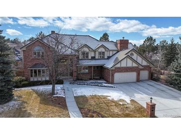 Beautiful brick home showcasing a well-manicured lawn, mature trees, and a spacious driveway at 6414 E Stanford Ave, Cherry Hills Village, CO 80111