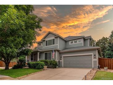Charming two-story home with a well-manicured lawn, mature trees, and a welcoming two-car garage during sunset at 5473 W Prentice Ct, Littleton, CO 80123