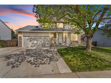 Charming two-story home with stone accents, lush green lawn, and mature tree at 524 Rider Ridge Dr, Longmont, CO 80504