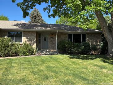 Charming brick home with a well-manicured lawn and mature trees providing shade at 1602 S Lamar St, Lakewood, CO 80232