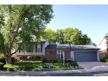 Charming home featuring brick and siding, a well-manicured lawn, beautiful foliage, and an attached two-car garage at 308 Baron Ave, Lafayette, CO 80026