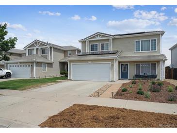 Two-story home featuring solar panels, an attached garage, landscaping, and a welcoming blue front door at 20765 E 39Th Ave, Denver, CO 80249
