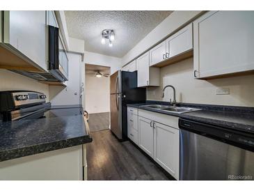 Kitchen featuring white cabinets, stainless steel appliances, and black countertops at 4569 S Lowell Blvd # B, Denver, CO 80236