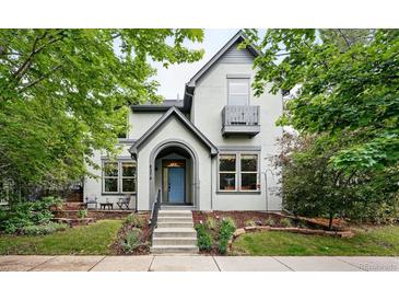 Charming two-story home with light grey exterior and a inviting front porch and a light blue front door at 8276 E 28Th Dr, Denver, CO 80238