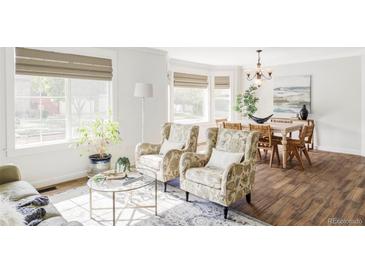 Bright living area featuring a bay window, hardwood floors, and elegant decor with a dining space at 6385 S Nelson Way, Littleton, CO 80127