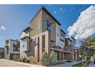 Modern three story townhome featuring mixed material exterior with brick, composite, and large windows under a bright blue sky at 3795 Depew St # D, Wheat Ridge, CO 80212
