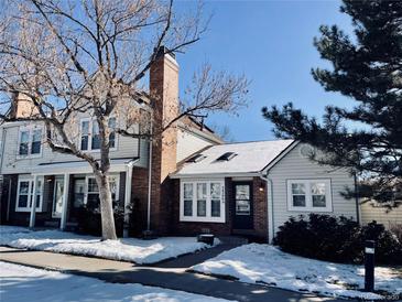 Charming townhome featuring a brick chimney and snow-covered front yard at 14396 E Temple Pl # A, Aurora, CO 80015