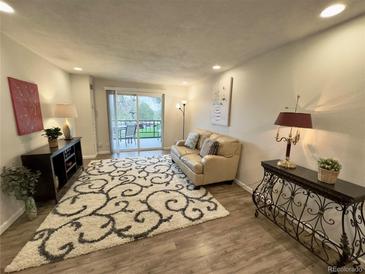 Bright living room features hardwood floors, comfortable seating, and a sliding glass door to the outdoor patio at 2325 S Linden Ct # 211, Denver, CO 80222