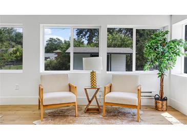 Bright living room features large windows, hardwood floors, and two plush chairs with a stylish center table at 5576 E Lehigh Ave, Denver, CO 80237